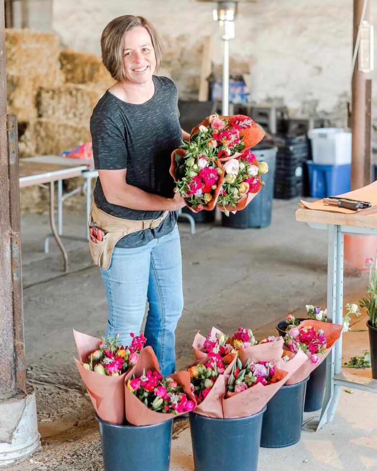 Lady from Riverside Blooms holding a bouquet of flowers at a growers market